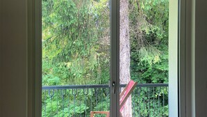 A room with a sliding glass door leading to an outdoor area with a wooden chair and a metal railing. - Spacious and bright apartment surrounded by greenery 10 minutes from Varese (Valganna)
