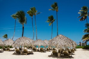 A beach with thatched umbrellas and sun loungers. - Iberostar apartment at Bavaro beach - perfect vacation with family and friends. (Punta Cana)