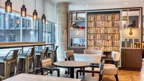 A modern library with bookshelves, seating, and pendant lights. - Premier Inn Dublin Cc Gloucester St South (Dublin)