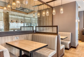 A restaurant with booths, hanging pendant lights, and a large mirror reflecting the interior. - Premier Inn Dublin Cc Gloucester St South (Dublin)
