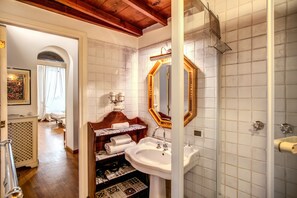 Ein Badezimmer mit weiß gefliester Wand, einem Holzwaschtisch, einem großen Spiegel und einem Waschbecken.