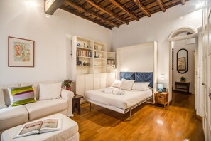 Ein Schlafzimmer mit einem Bett, einem Sofa, einem Bücherregal und einem kleinen Tisch.