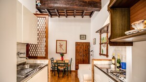 Une cuisine avec un plafond en bois, une table à manger avec des chaises, un évier et une cuisinière.