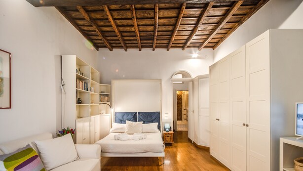 Une chambre à coucher avec un lit, une armoire blanche, un canapé blanc et un plafond en bois.