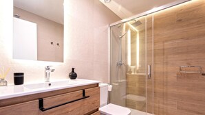 Une salle de bain moderne avec un meuble-lavabo en bois, une cabine de douche en verre et des toilettes.