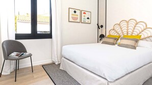 Ein Schlafzimmer mit einem Bett, einem Stuhl, einem Fenster und zwei an der Wand befestigten Bildern.