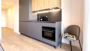 Eine moderne Küche mit grauen Schränken, einem eingebauten Ofen und einem Holzbodenoberschrank.