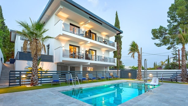 A modern two-story house with a swimming pool, outdoor seating, and palm trees. - Genteel Home Arruzafa I (Cordoba)
