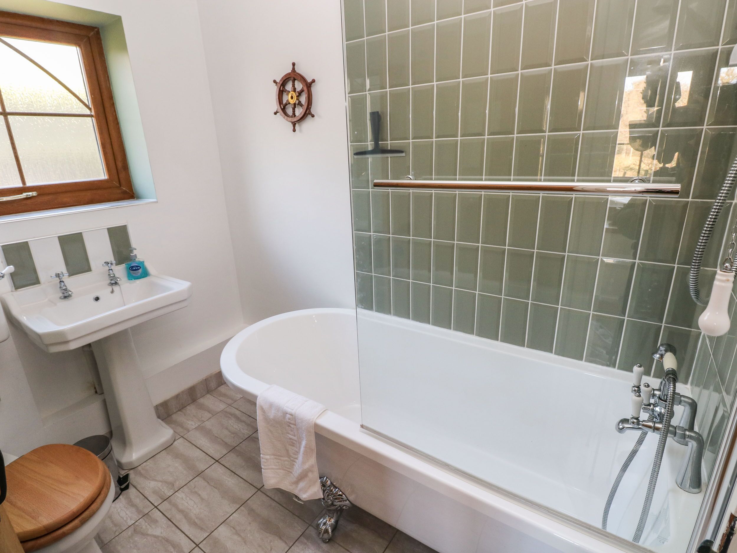 A bathroom with a white sink, a wooden toilet, a bathtub, and a shower area.