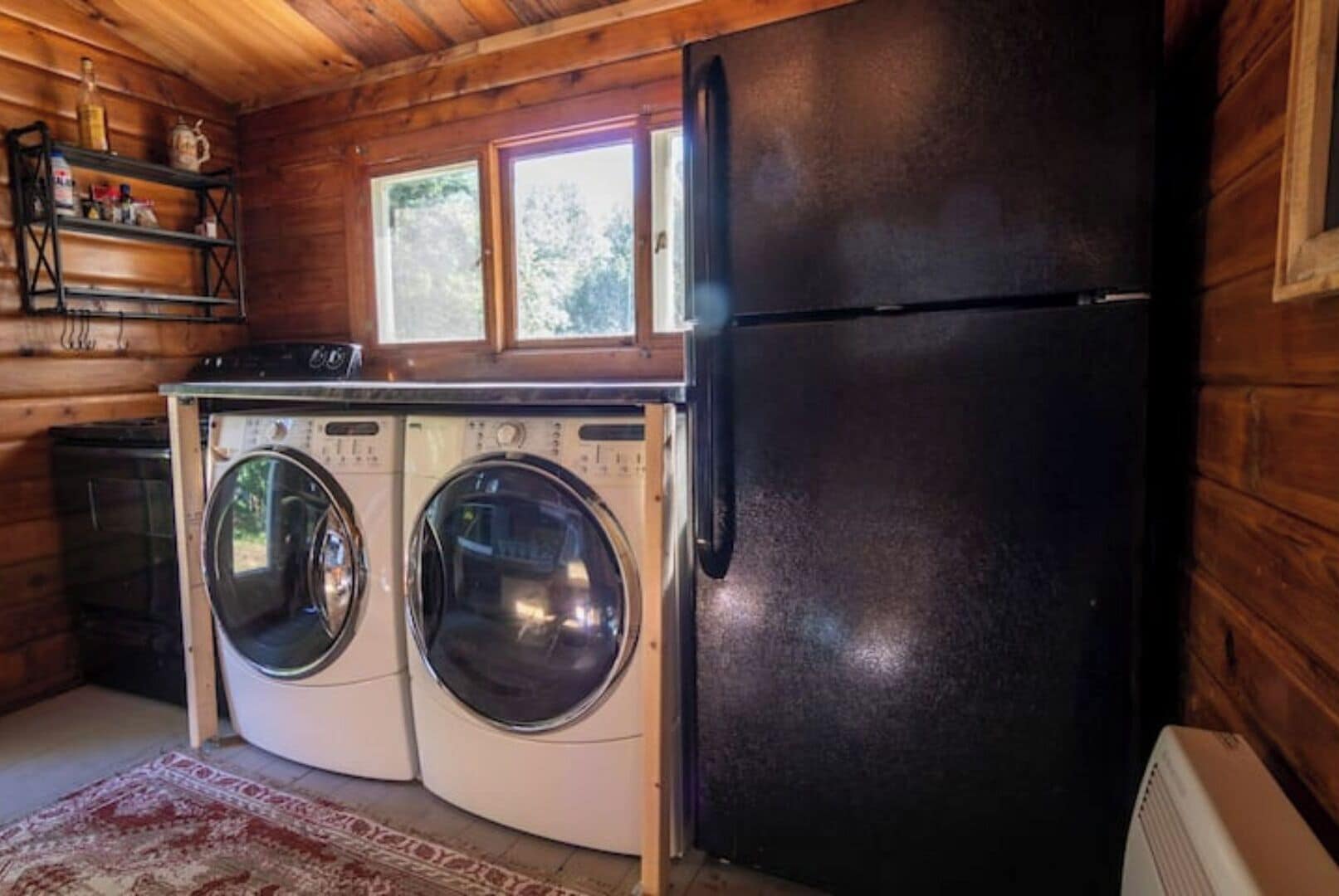 A compact kitchen with a washing machine, a refrigerator, and a window above the sink.