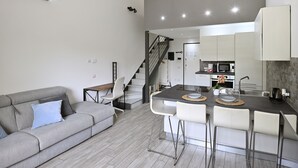 A modern kitchen with a central island, white bar stools, and a staircase leading to an upper level. - Boutique Apartment "Divided Two" in Florence (Firenze)