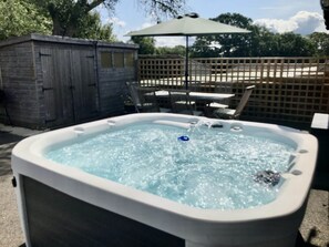 Un bain à remous doté d’une structure en bois et d’un espace extérieur aménagé pour s’asseoir.