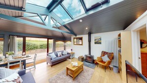 A spacious living area with a large window, a sofa, a coffee table, and a fireplace. - Arniss - sleeps 20 guests  in 9 bedrooms (Fordingbridge)