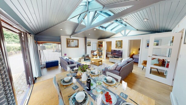A spacious living area with a high ceiling, a dining table set for four, a sofa, and a television. - Arniss - sleeps 20 guests  in 9 bedrooms (Fordingbridge)