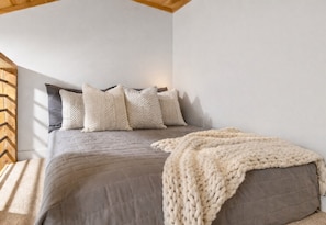 Quarto com cama, almofadas e cobertor.