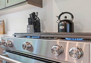 Une cuisinière en acier inoxydable dotée de quatre boutons et sur laquelle est posée une bouilloire.