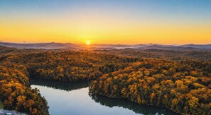 Une vue panoramique d’un paysage boisé, avec un lac et des montagnes à l’horizon.