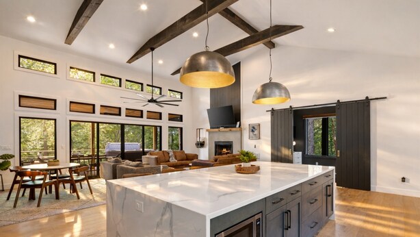 Cucina spaziosa con isola centrale ampia, travi in legno e illuminazione a sospensione.
