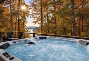 A hot tub with a view of a forest and a lake.