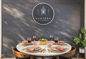A dining table set with plates, glasses, and cutlery, with a logo above. - Lantern Landing: Lake Views meet Elevated Style • HotTub • FirePit • Games (Morganton)