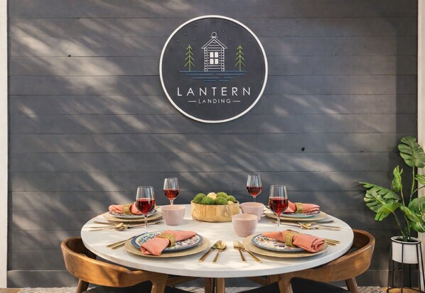 Une table à manger dressée avec des assiettes, des verres et des couverts, et un logo placé au-dessus.