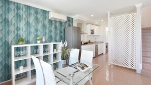 Moderni keittiö, jossa on valkoiset kaapit, ruostumattomasta teräksestä valmistettu jääkaappi ja mikroaaltouuni.