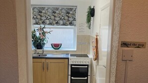 Una cucina compatta con mobili in legno, forno a incasso e piano di lavoro in pietra.
