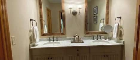Un baño con dos lavamanos, un espejo grande y un armario de madera.