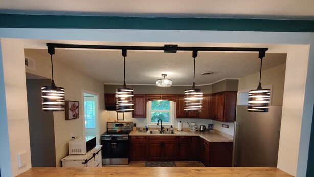 Une cuisine moderne avec des meubles en bois, un îlot central et des luminaires suspendus.