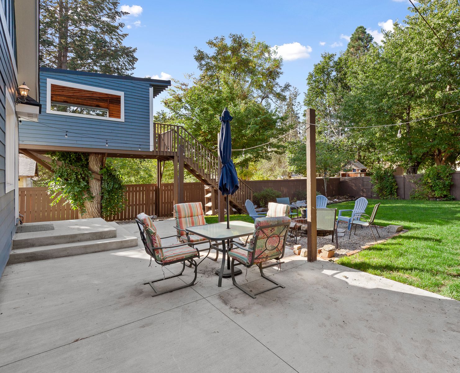 A backyard patio with a table and chairs, a covered seating area, and a wooden deck.