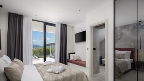 Une chambre d’hôtel moderne dotée d’un grand lit, d’un canapé, d’une télévision et d’une douche à parois de verre.