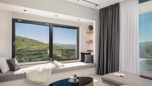Un salon moderne doté d’une grande fenêtre, d’un canapé, d’une table basse et offrant une vue sur un paysage verdoyant.