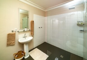 Un baño con lavamanos, espejo y ducha.