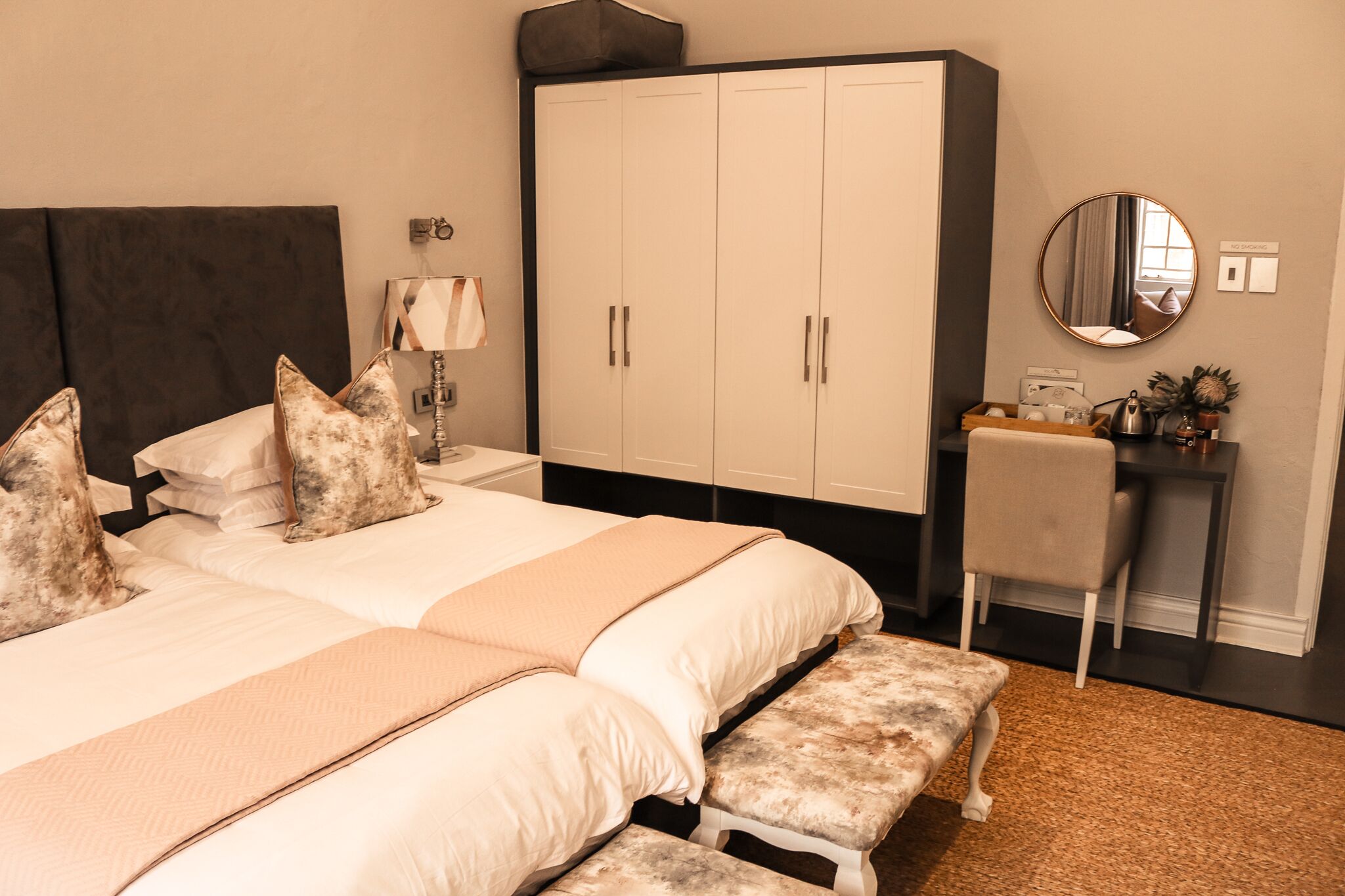 Een slaapkamer met een groot bed, een garderobe, een bureau en een spiegel.