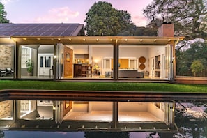 Una casa moderna con fachada de vidrio, piscina y panel solar en el techo.