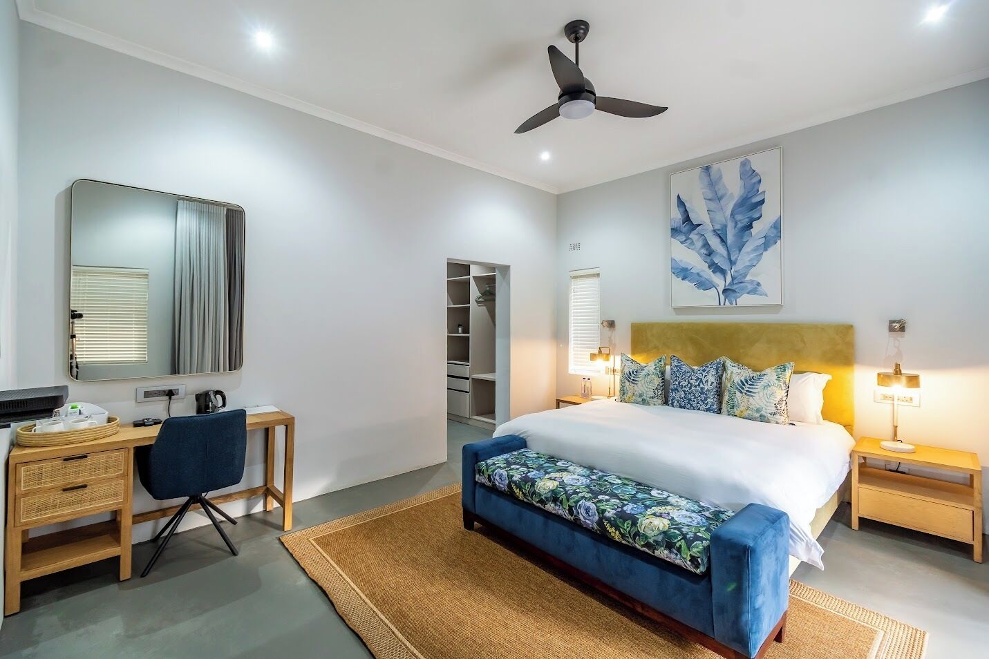 A modern bedroom with a bed, desk, chair, and a ceiling fan.