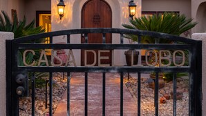 A gated entrance with the sign "CASA DELLOBO" and a pathway leading to a building with a tiled roof and arched doorways. - Casa Del Lobo - Private Spanish Oasis Getaway (Palm Springs)