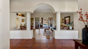A spacious foyer with a high ceiling, a central archway, and a view into an outdoor patio area. - Casa Del Lobo - Private Spanish Oasis Getaway (Palm Springs)