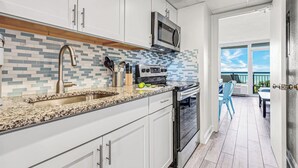 Une cuisine moderne avec des meubles blancs, un plan de travail en granit, un four à micro-ondes et un four traditionnel.