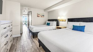Une chambre d’hôtel avec deux lits, une commode et une vue sur l’extérieur.