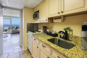 A kitchen with a granite countertop, stainless steel sink, and a Keurig coffee maker. - Double Palms by StayMareni - Oceanfront Suite (Myrtle Beach)