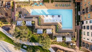 An aerial view of a hotel with a central swimming pool, surrounded by lounge areas and greenery. - Plano Tourist Hot Spot! (Plano)