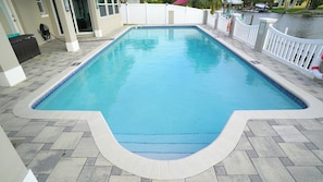 A rectangular swimming pool with a white deck and a white fence surrounding it. - "Dive Into Fun! Spring & Summer Deals at Dolphin Cove – Walk to It All!" (Cocoa Beach)