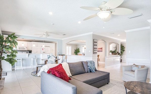 A spacious living room with a gray sectional sofa, a coffee table, and a ceiling fan. - "Dive Into Fun! Spring & Summer Deals at Dolphin Cove – Walk to It All!" (Cocoa Beach)