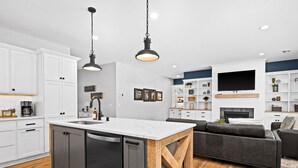 A modern kitchen with white cabinets, a central island, and pendant lighting. - Jay Cooke Park and Spirit Mtn Retreat with wood-burning sauna and game room  (Esko)