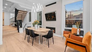 A modern dining area with a wooden table and black chairs, a fireplace, and a large window with a view.