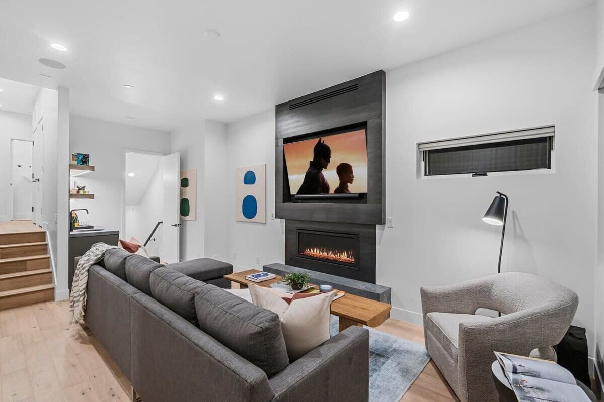A modern living room with a fireplace, a sofa, a coffee table, and a TV mounted on the wall.