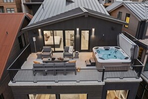 A modern rooftop terrace with a hot tub, outdoor seating, and a view of the cityscape. - The Kings Crown | Brand New Ski In Out 4BR at PCMR (Park City)
