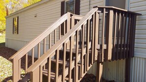 A wooden staircase leading up to a house with a white exterior and a brown roof.