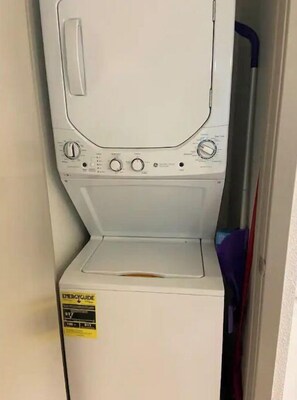 Compact laundry room with a front-loading washing machine and control panel.